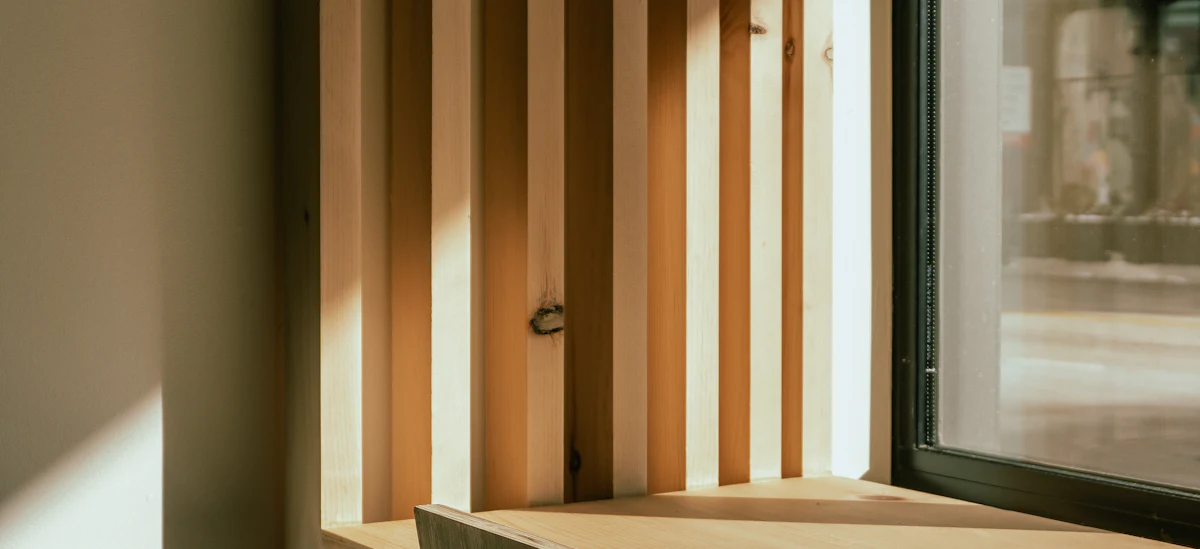 Mesa de trabajo de madera junto a una ventana con luz natural entrando de lado